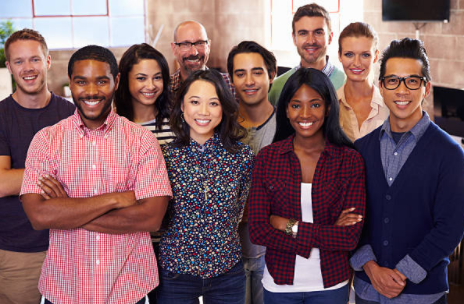 Diverse group of people standing in an office setting and smiling at camera