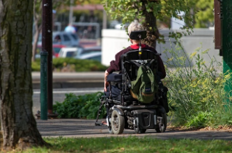 Photo of a person in a wheel chair on the sidewalk Photo of a person in a wheel chair on the sidewalk