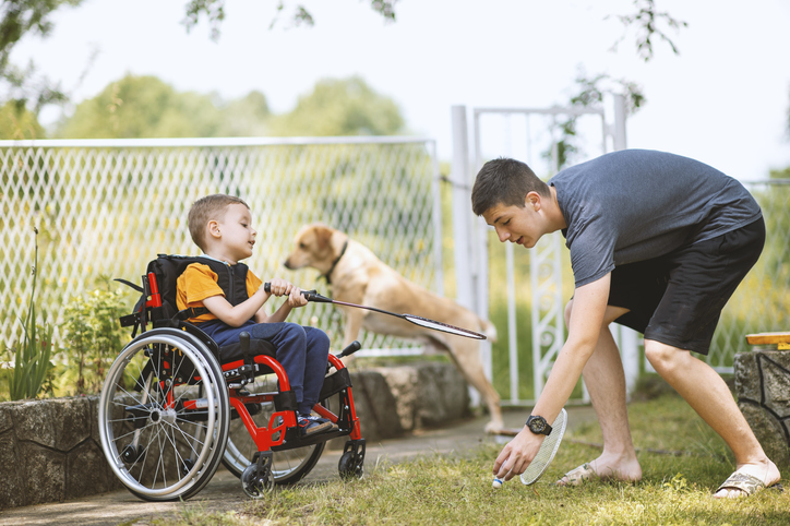 Father playing soccer outside with his son and daughter