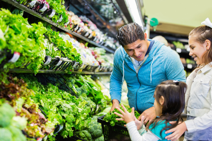 Father shopping with daughters for groceries in local supermarket