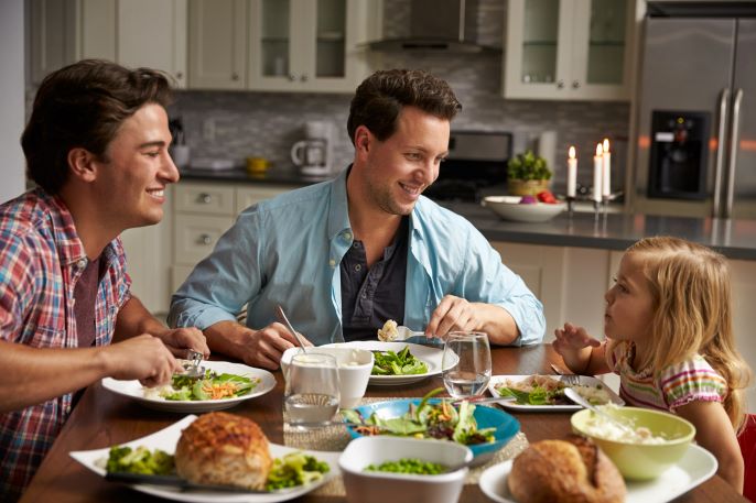 Male gay couple and daughter dining in their kitchen