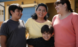 Family of four smiling at the camera hugging each other