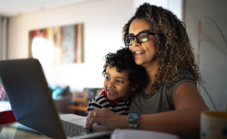 Mother looking at laptop with small child on her lap