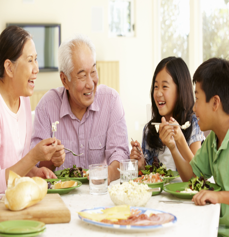 Family gathered around an elderly woman celebrating her birthday outdoors, with a cake and decorations on the table.