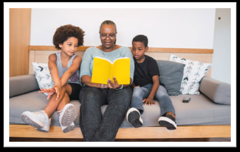 Older woman sitting on couch and reading a book to two children