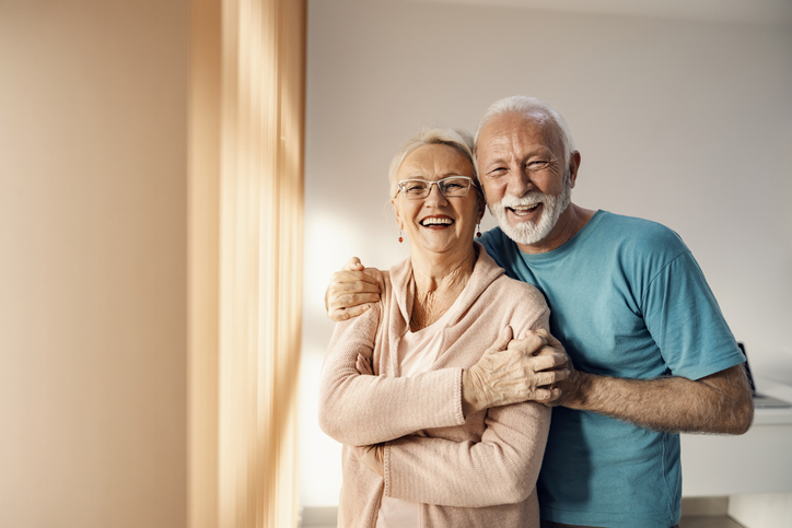 Older Couple hugging and smiling at camera