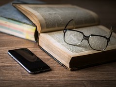 Image of cell phone, glasses and book