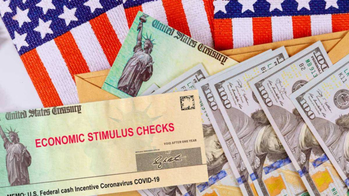 Stimulus checks and cash resting on the American flag Stimulus checks and cash resting on the American flag